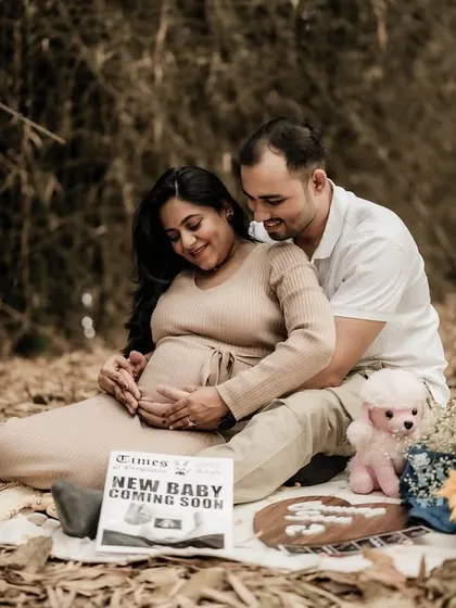 A beautiful, full-scene shot of the couple enjoying their picnic announcement in the woods. The setting is rustic and romantic.