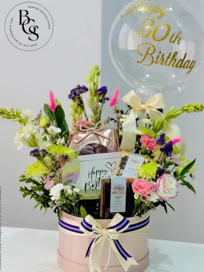A spectacular 30th birthday hamper designed to wow. This large pink hatbox is overflowing with fresh flowers, curated gifts, and a personalized balloon, making it the ultimate celebratory statement piece.