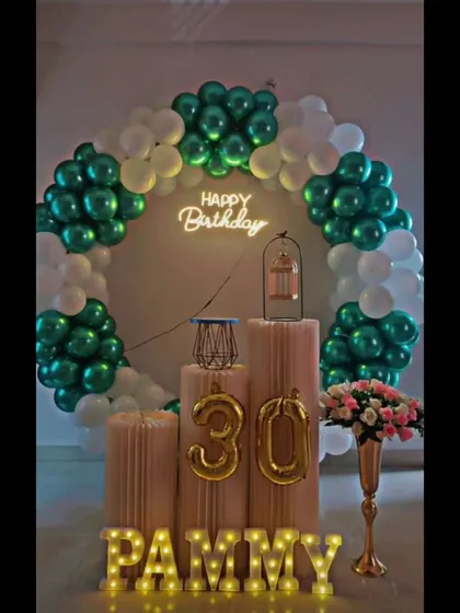 A cool and classy 30th birthday setup with a green and white balloon ring, a 'Happy Birthday' neon sign, and foil balloon numbers.
