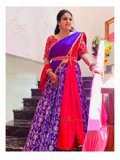 Our client Poorva looks stunning on the stairs in her custom red and purple half saree, complete with an embroidered blouse and waistband.