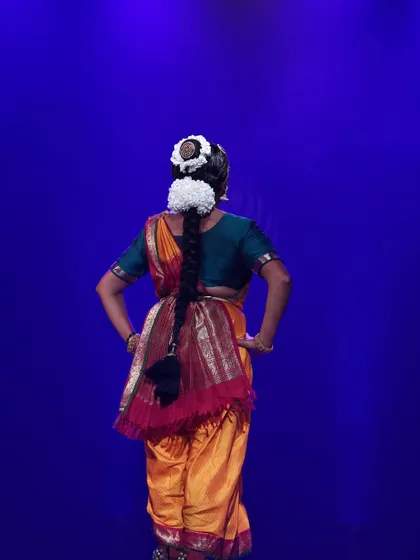 A view from the back, showcasing the traditional hairstyle and costume details. Every element of the Aharya, or costume and adornment, is carefully considered to complete the visual poetry of the dance.
