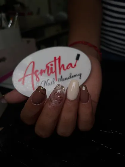A closer view of our acrylic nail extensions, showcasing a mix of matte brown, creamy off-white, and a translucent nail with embedded glitter.
