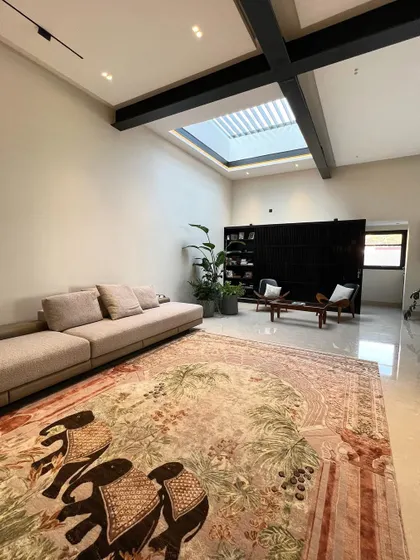 A Saturday afternoon well spent adding greenery to this double-height living room. The large skylight floods the space with natural light, highlighting the grand scale and the beautiful custom elephant-motif rug.
