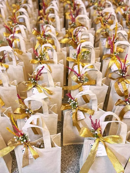 A sea of thamboolam bags ready for a large event. The combination of jute, dried flowers, and golden ribbons creates a look of rustic elegance.