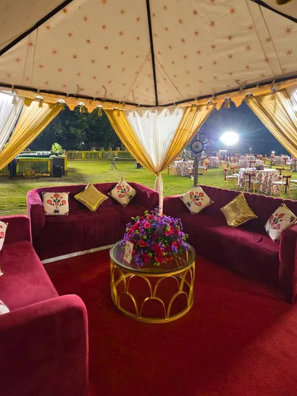 A luxurious cabana seating area for the Sufi Sangeet. The deep red velvet sofas, custom-printed cushions, and elegant tent create a cozy and royal lounge space for guests.