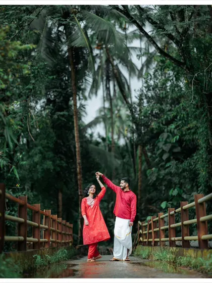 A romantic dance on a bridge surrounded by lush greenery and palm trees, a perfect moment from a monsoon pre-wedding shoot.