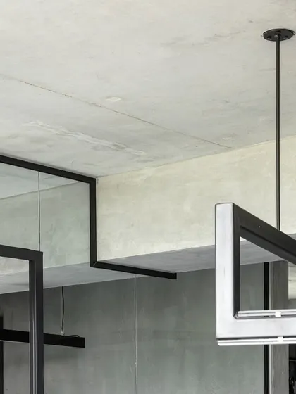 A detail showing the intersection of a custom steel light fixture and a glass partition in our studio. This highlights our attention to detail and the careful integration of different architectural elements.