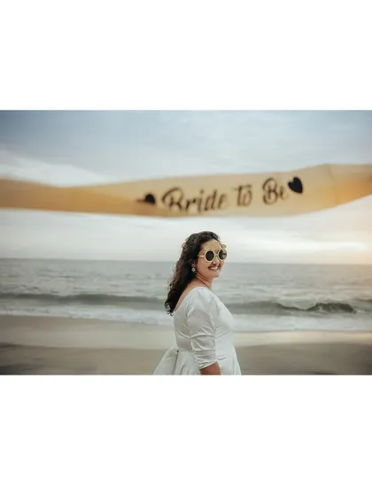 The bride-to-be posing with her sash on the beach, her smile full of excitement.