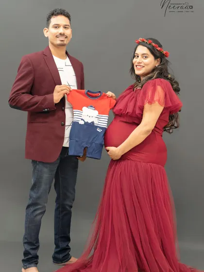 "Look what we're waiting for!" Holding up a tiny baby outfit is such a sweet and tangible way to celebrate the little one on the way. It makes the moment feel so real and exciting.