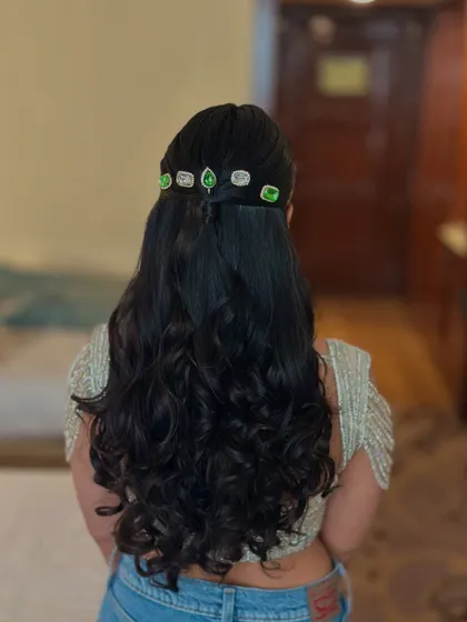 A simple half-up style with soft curls, made unique with a line of green and white stone accessories.