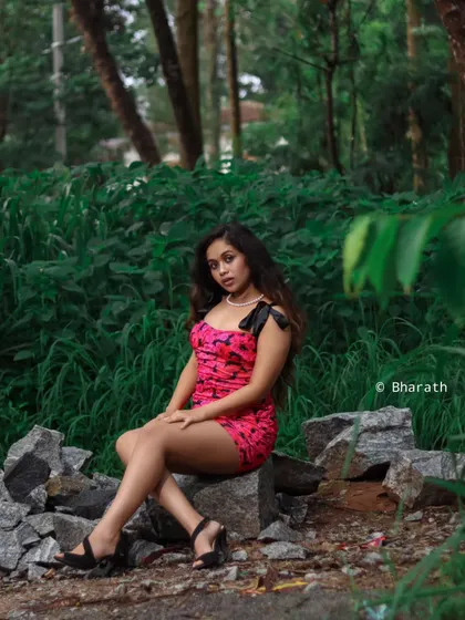 A full-length portrait in a natural, rocky setting. The contrast between the dressy outfit and the rugged environment creates a striking image.