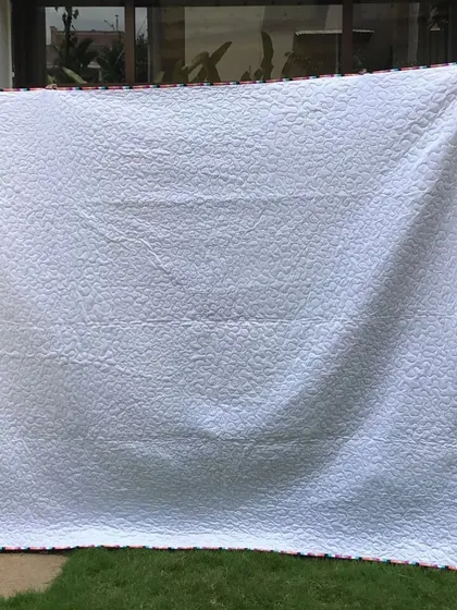 The simple white backing of the floral quilt.