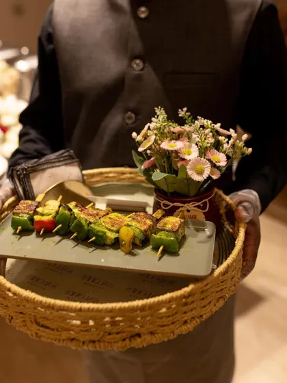 A server holding a tray of Paneer Tikka Skewers. My professional team ensures that pass-around appetizers are served with elegance and a smile.
