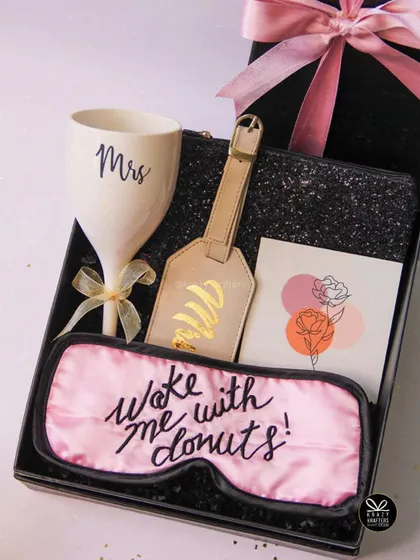 "Woke me with donuts!" A fun and flirty hamper for the bride-to-be, including a 'Mrs' wine glass, a personalized luggage tag, and a cheeky sleep mask.