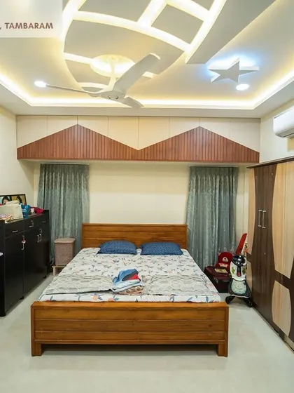 A kids' bedroom in the Tambaram villa, featuring a wooden bed, a two-tone wardrobe, and a creative false ceiling design with star and airplane motifs.