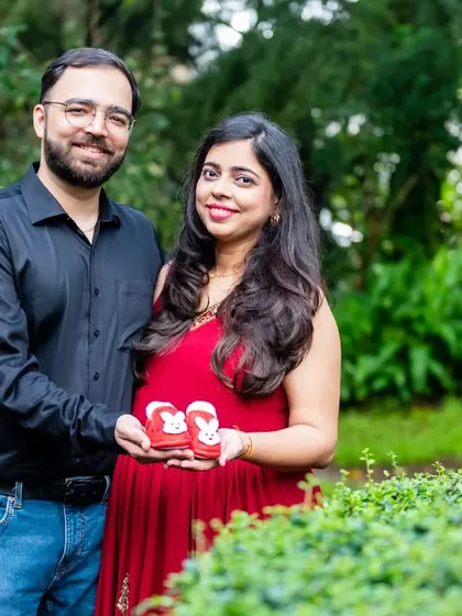 Holding up a pair of tiny red baby shoes is a sweet and symbolic way to announce the coming arrival. This couple's portrait is full of warmth and happiness.