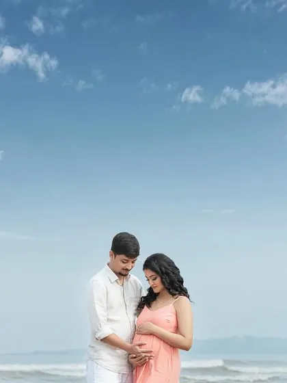 A quiet moment of connection on the sand, both looking down at the life they've created together.
