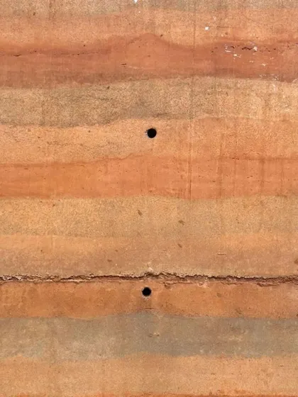 A close-up of the stratified layers of a rammed earth wall, a technique that is both sustainable and visually stunning.
