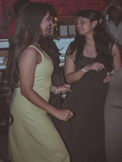 Two guests chatting and dancing. The dim lighting and party atmosphere create an intimate yet energetic setting.