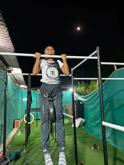 Weighted pull-ups under the moonlight. This young girl is building serious strength and is not afraid to take on a challenge.