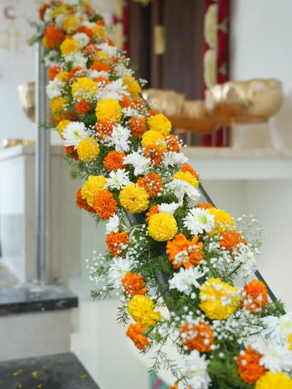 For a traditional housewarming, I created this beautiful floral garland for the staircase using marigolds and white chrysanthemums. It's a classic and vibrant way to welcome guests into a new home.