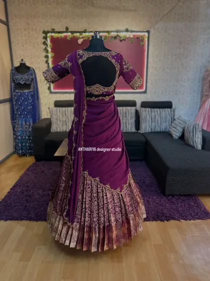 The back view of a deep purple langa voni, showing the intricate embroidery on the blouse and the elegant drape of the davani.