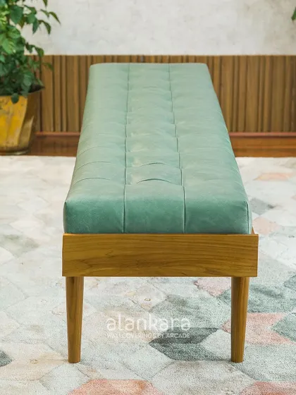 The Colmar bench, a longer version of the stool, perfect for entryways or at the foot of a bed. Its teak frame and green leatherette upholstery offer both style and durability.