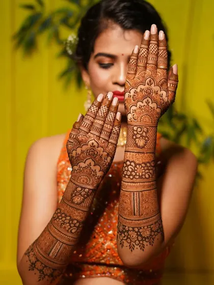 This is a beautiful example of a semi-filled bridal design. It focuses on delicate floral bands and patterns, leaving some skin visible for a lighter, more contemporary feel.