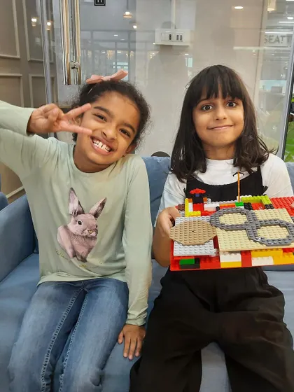 Two happy builders showing off their awesome LEGO creation. Teamwork makes the dream work, and our workshops are a great place for kids to collaborate and make new friends.