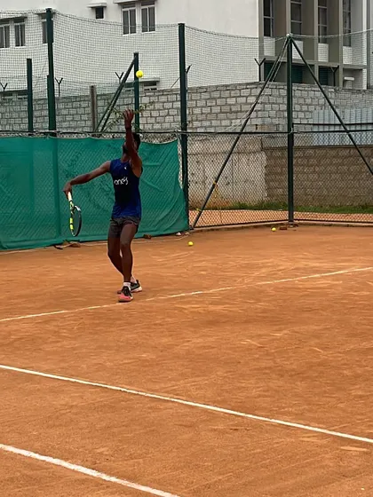 The peak of the service motion. This image captures the extension and power generated during a serve, a key focus in our high-performance training.