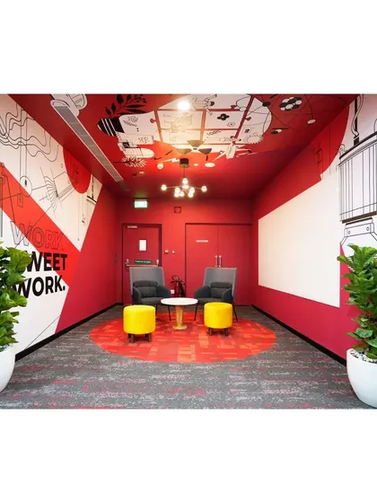 A breakout area with bold red walls and a graphic mural on the ceiling. We designed this space to be an immersive visual experience, perfect for sparking creativity and informal brainstorming.