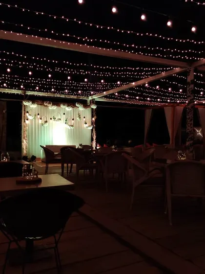 The same engagement party setup at night, showing how the fairy light canopy creates a magical, starry effect. The lighting is key to transforming the mood of the space after sunset.