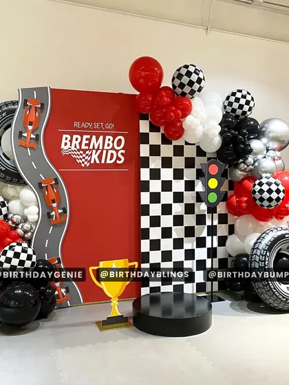 A "Ready, Set, Go!" race car party with a large red backdrop and a checkered flag panel. The trophy and tire props make every guest feel like a winner.