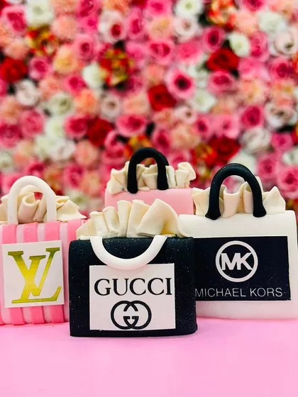 A close-up of the edible, handcrafted shopping bags from luxury brands like Louis Vuitton, Gucci, and Michael Kors. The detail on these fondant toppers is incredible.