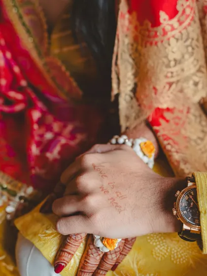 A sunny Haldi ceremony in the British countryside, with details like "Love is all we need" henna, fresh yellow flowers, and bowls of rose petals.