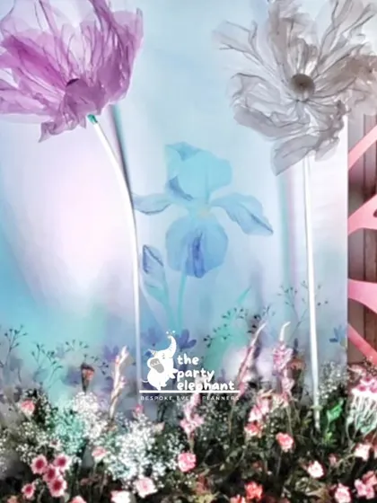 A close-up of the detailed backdrop, featuring large organza flowers, butterfly wing cutouts, and fresh floral arrangements at the base. These elements add texture and depth to our fairy party designs.