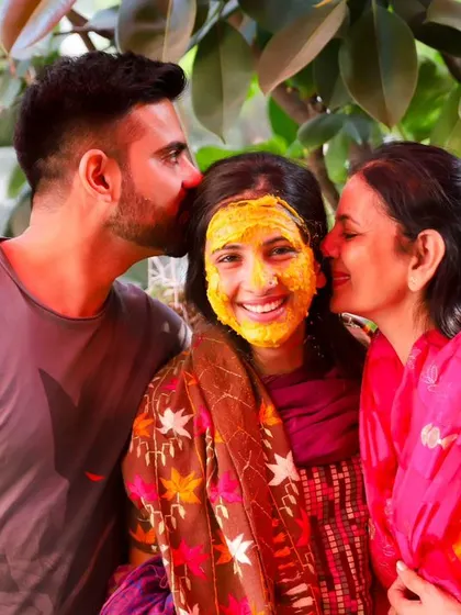 A beautiful family portrait from the Haldi ceremony. The bride is showered with kisses from both sides, a perfect picture of family love and happiness.