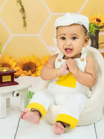 This baby boy is all smiles, looking happy and content in his sunny, sunflower-themed photoshoot.