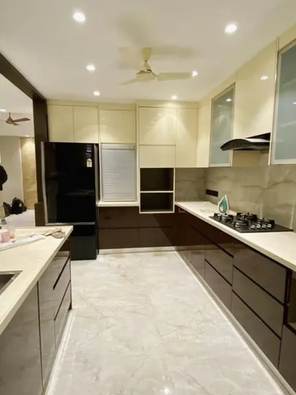 This spacious kitchen in Vasant Kunj uses a beautiful combination of glossy brown and cream cabinets. The design includes an open partition that elegantly separates the kitchen from the dining area.