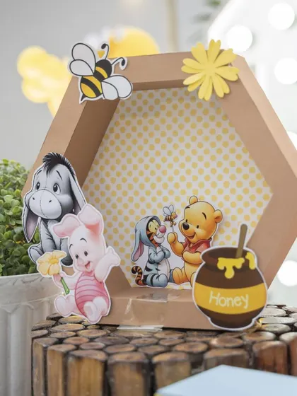 A sweet detail from a 'Winnie the Pooh' party. This hexagonal prop features Pooh, Piglet, Tigger, and Eeyore, adding a touch of the Hundred Acre Wood to the decor.