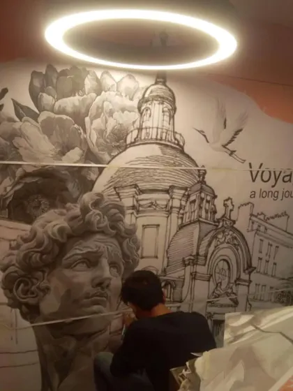 An artist from my team meticulously working on the 'Raahi' travel-themed mural. This section features a tribute to classical art and architecture.
