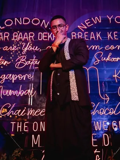 A stylish groom posing in front of a custom neon sign at the sangeet. We capture the cool, personalized details that make your event unique.
