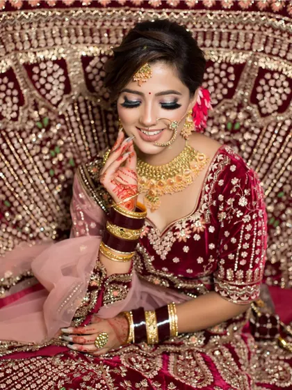 A candid moment of a bride looking down, showcasing the detailed eyeshadow work and the beautiful floral hair accessories. The overall look is soft, romantic, and very elegant.