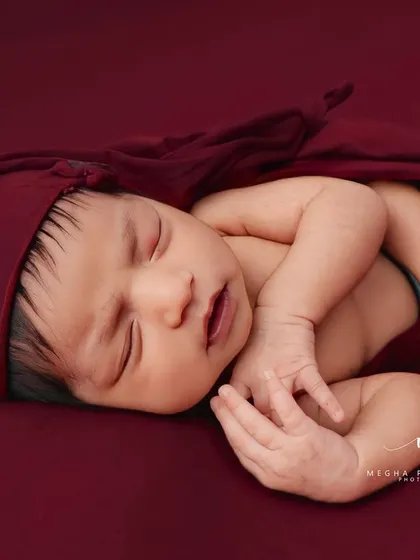 This pose, with hands gently placed near the face, looks incredibly peaceful and natural. The matching red hat completes the adorable look.