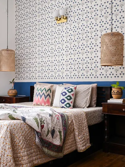 This guest bedroom uses a subtle, stylish printed wallpaper and low-hanging cane pendant lights to create a cozy, rustic feel.