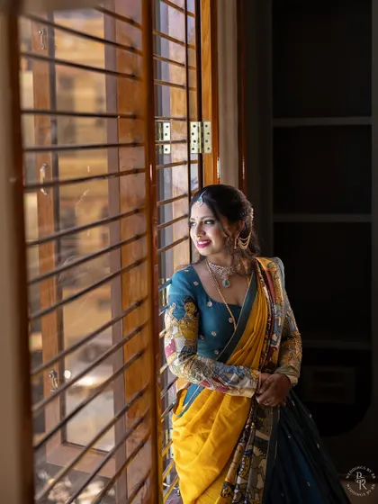 A beautiful portrait of a woman by the window. The soft, natural light illuminates her features and the intricate details of her colorful traditional half-saree.