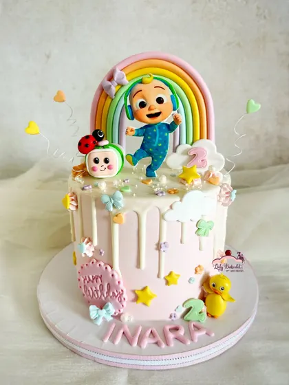 Another adorable Cocomelon cake, this time for a little girl. This design features a pink drip, pastel rainbow, and cute characters like the ducky and ladybug.