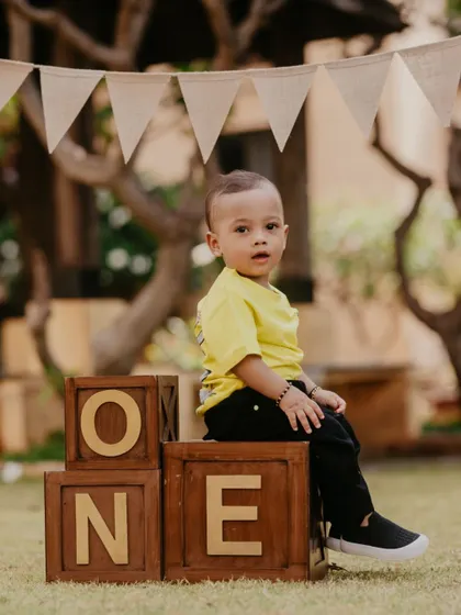 A classic first birthday portrait. This little boy sits proudly atop wooden blocks that spell out "ONE" in a lovely garden setting.