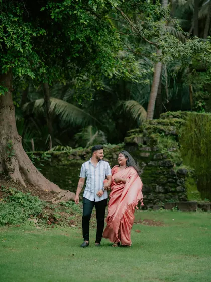 A couple walks through a lush green park, a classic and timeless pre-wedding photograph.