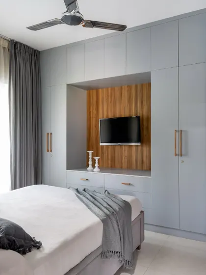 This wardrobe in the matriarch's room includes an integrated TV unit with a wood-paneled backdrop, making it a functional and space-saving feature.